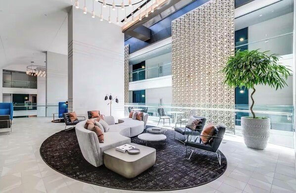 Relax in the stylish lobby with a comfortable seating area, large wall art, and a balcony offering a view of the city.