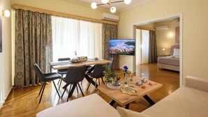 A living room with a wooden floor, a dining table with chairs, a TV, and a sofa. - Blue Ark Acropolis Signature Residence (Athens)