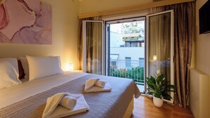 A hotel room with a bed, a potted plant, and a view through a sliding glass door. - Blue Ark Acropolis Signature Residence (Athens)