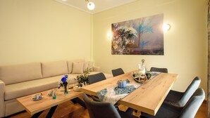 A dining area with a wooden table, chairs, and a sofa. - Blue Ark Acropolis Signature Residence (Athens)