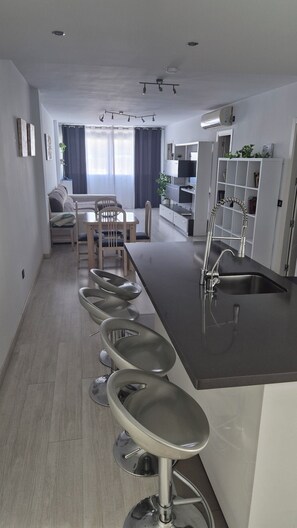 A modern kitchen with a central island, bar stools, and a built-in sink. - In the center of town, Edif. Penibética, Bulevar de la Cala de Mijas, (La Cala de Mijas)