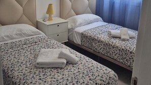 A hotel room with two beds, a nightstand, a lamp, and a ceiling light.
