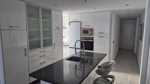A modern kitchen with a black countertop, stainless steel appliances, and a microwave.