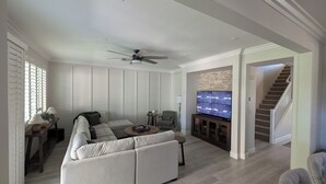 Amplia sala de estar con un sofá seccional grande, un televisor de pantalla plana y un ventilador de techo.