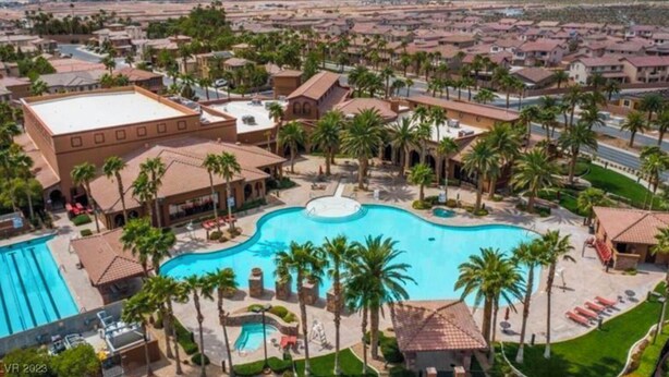 Un resort con una gran piscina central, palmeras y montañas al fondo.