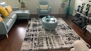 A living room with a blue sofa, a blue armchair, a coffee table, and a patterned rug.