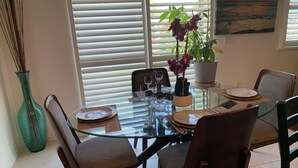 A dining area with a glass table, chairs, and a potted plant.