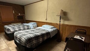Una habitación con dos camas, un escritorio, una silla, una lámpara y un televisor.