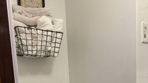 Un baño pequeño con inodoro, pared blanca y un cuadro enmarcado sobre el inodoro.