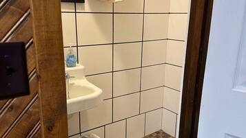 A small bathroom with a sink, toilet, and a trash bin.
