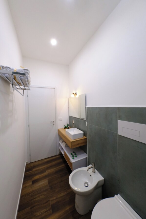 A compact bathroom with a wooden vanity, a white sink, and a bidet. - AmaCasa Siracusa (Syracuse)