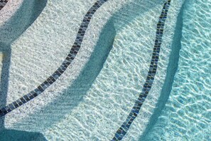 Una piscina con agua cristalina y borde de azulejos.
