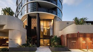 A modern hotel with a curved facade, large windows, and a well-lit entrance. - Vue Broadbeach - Official (Broadbeach)