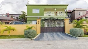 Une maison à deux étages, dotée d’une entrée fermée par un portail, d’un balcon à l’étage supérieur et d’une allée menant au portail.