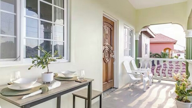 Un balcon avec des chaises blanches et une plante en pot.