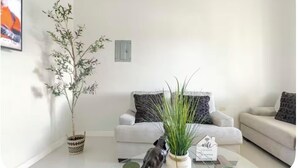 Un salon moderne avec un canapé, deux tables d’appoint et des plantes décoratives.