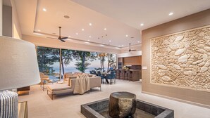 A modern living room with a stone fireplace, a dining area, and a kitchen.