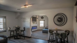 A modern dining area with a bar, multiple seating options, and a decorative wall piece. - Luxury Meets Historic @ The Luxe Loft - AMAZING LOCATION! (Algoma)