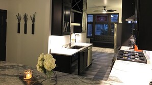 A modern kitchen with a central island, black cabinetry, and a built-in oven. - Luxury Meets Historic @ The Luxe Loft - AMAZING LOCATION! (Algoma)