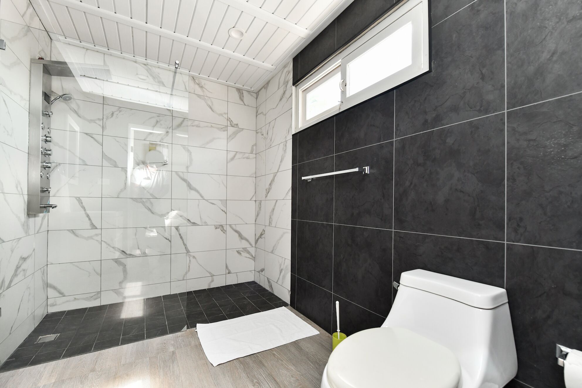 A modern bathroom with a glass-enclosed shower, a toilet, and a sink.