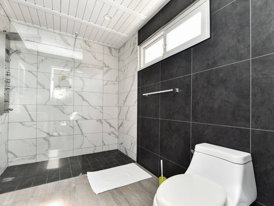 A modern bathroom with a glass-enclosed shower, a toilet, and a sink.