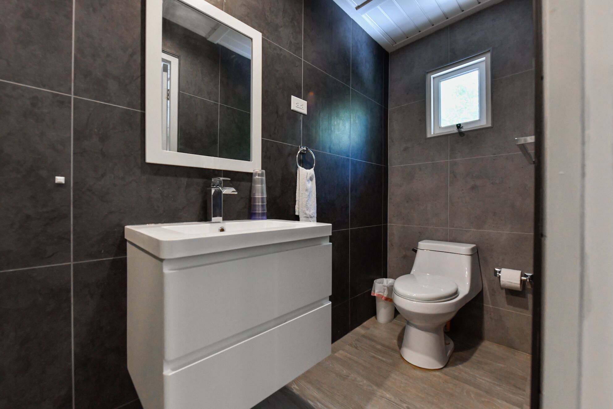 A modern bathroom with a white sink, a toilet, and a mirror.