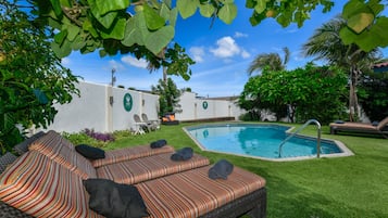 Relax by the serene pool surrounded by lush greenery and a stylish lounge area.