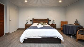 Un dormitorio ordenado con una cama grande, mesitas de noche con lámparas, una pequeña mesa redonda y una silla.