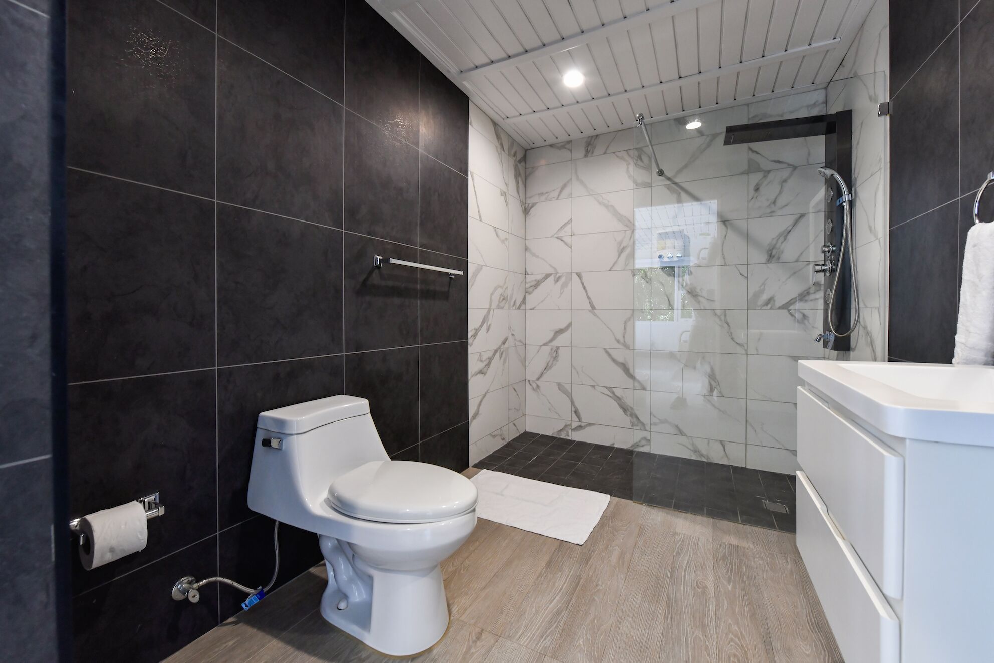 A modern bathroom with a toilet, shower, and sink.