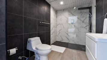A modern bathroom with a toilet, shower, and sink.