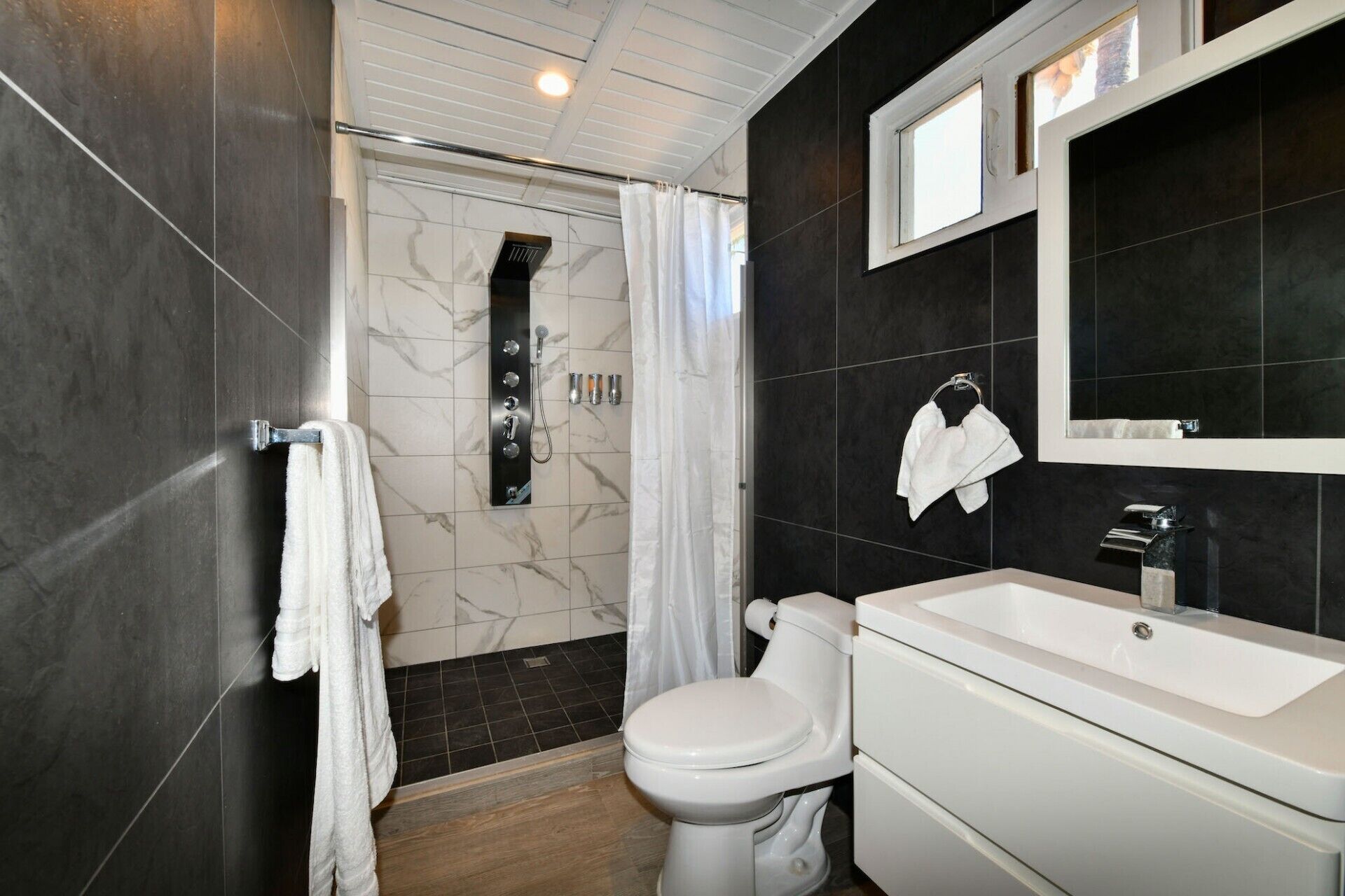 A modern bathroom with a shower, toilet, and sink.