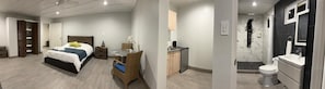 A modern hotel room with a bed, a dining table with chairs, a small kitchen area, and a bathroom with a shower and toilet. - ALOE B&B (Oranjestad)