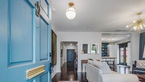 A modern living room with a blue door, a white sofa, a wooden coffee table, and a patterned rug.