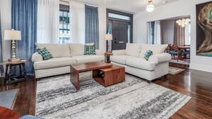 A modern living room with a sectional sofa, a coffee table, and a dining area with a chandelier.