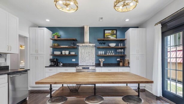 A modern kitchen with a central island, bar stools, and a large window.