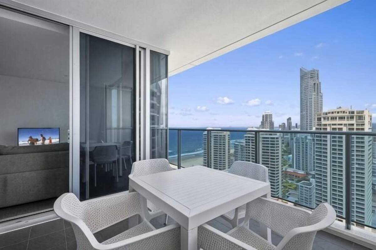 A balcony with a white table and chairs, a sofa, and a TV screen.