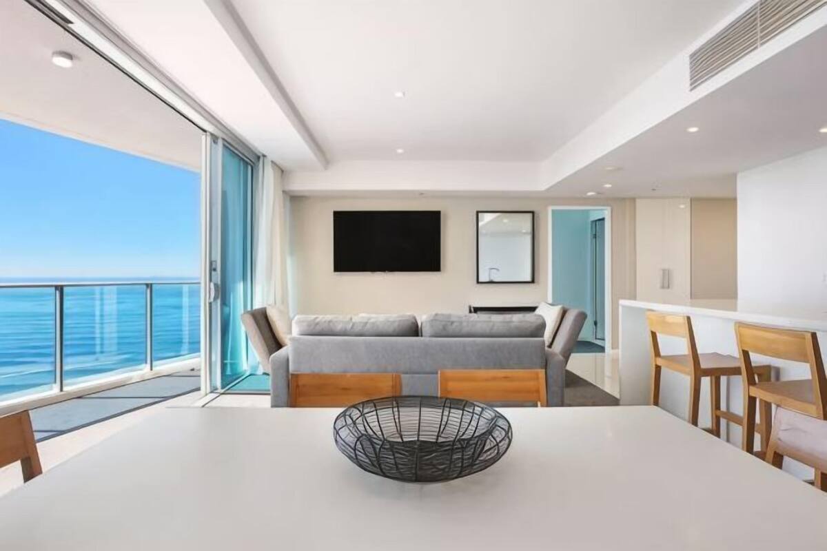 A modern interior with a balcony, a sofa, a dining table, and a TV.