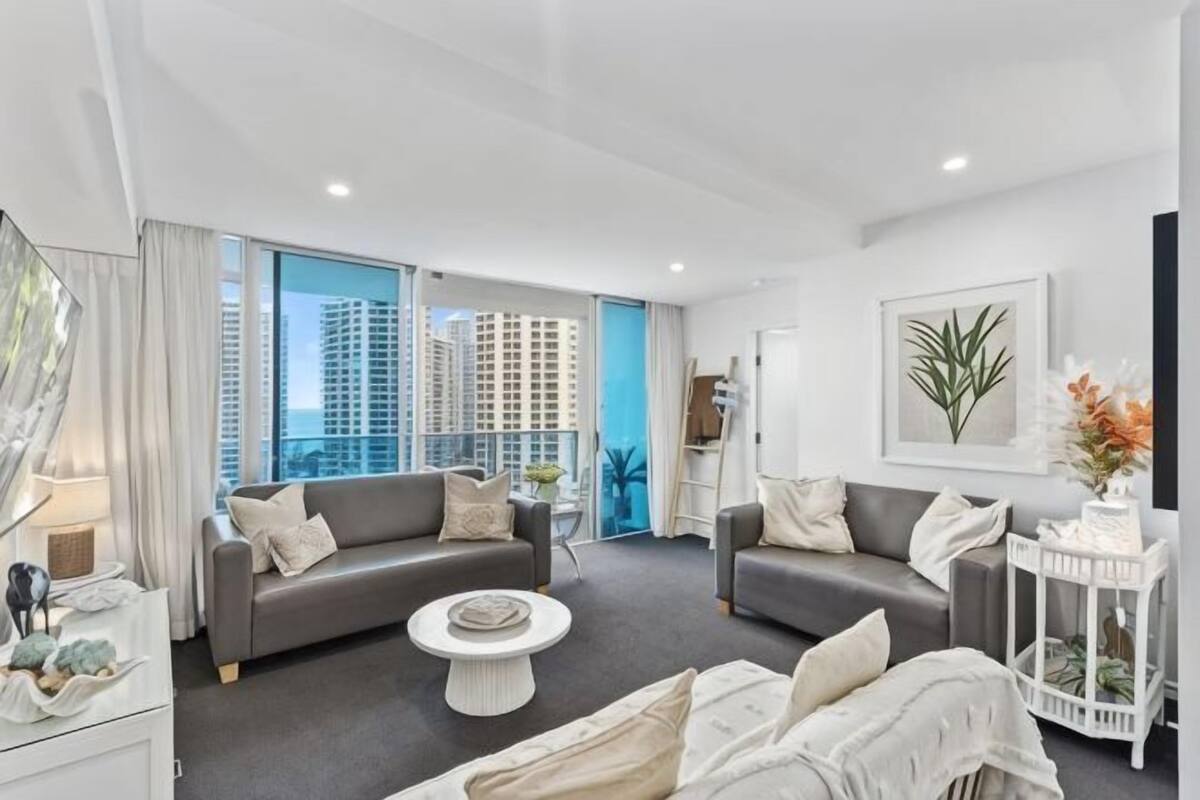 A modern living room with two sofas, a coffee table, and a view of high-rise buildings.