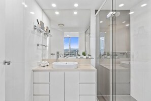 Un baño moderno con un espejo grande, un lavabo y una zona de ducha.