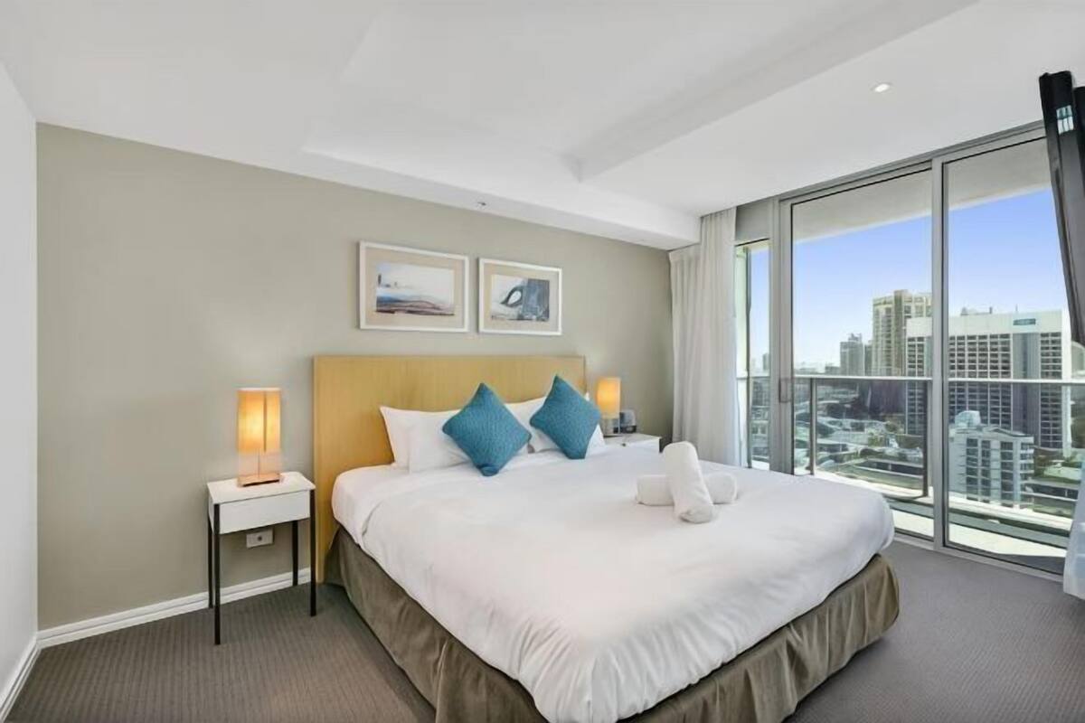 A hotel room with a large bed, two bedside tables, a city view, and a modern design.
