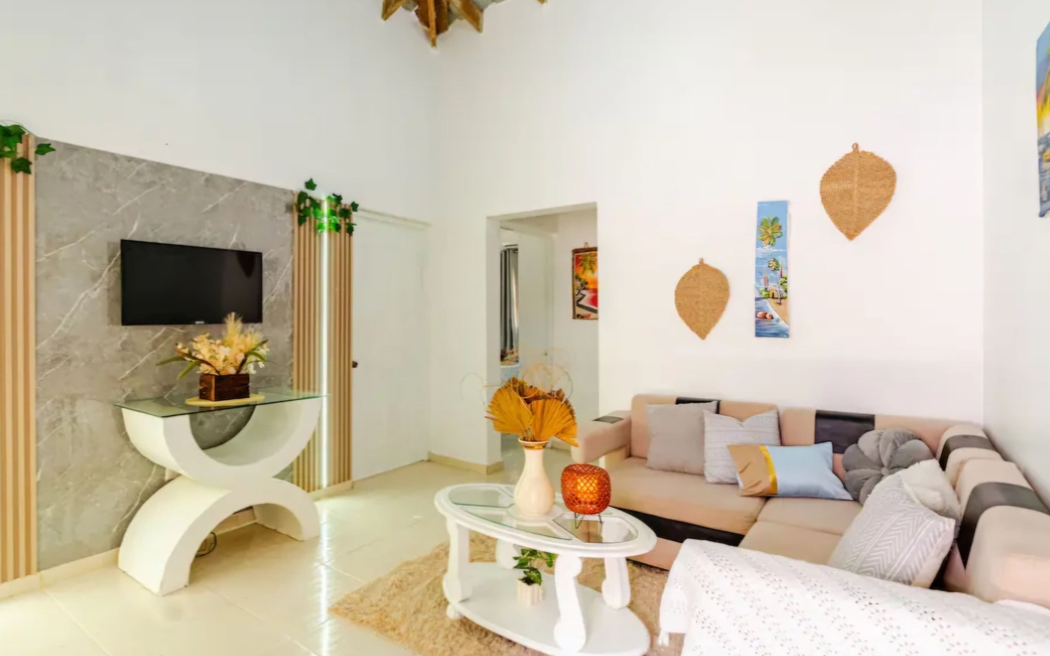 Un soggiorno moderno con un divano, un tavolino in vetro, una TV a parete e decorazioni murali.