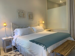 A neatly made bed with white linens and a blue throw, flanked by two bedside lamps. - New Luxe Condo | Gated | 5 min walk to Love Beach | Pool & Gym | Pet-friendly (West End)