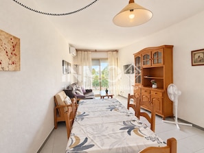 A spacious living area with a dining table, sofa, and a cabinet.