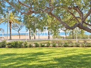 A grassy area with a fence, trees, and a view of the beach and ocean. - Golf Sant Jordi - La Llosa, sea views, parking  (Cambrils)