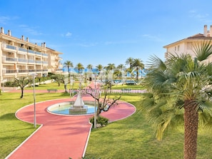 A hotel with a pool area, palm trees, and a clear sky.