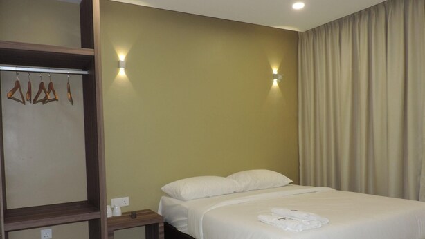A hotel room with a bed, a wooden wardrobe, and two wall-mounted lights. - Golden Leaf Boutique Hotel (Johor Bahru)