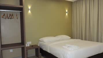 A hotel room with a bed, a wooden wardrobe, and two wall-mounted lights.