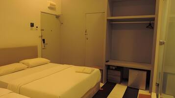 Une chambre d’hôtel avec deux lits, une armoire et un bureau.