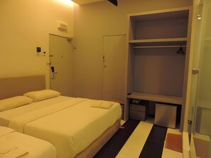Ein Hotelzimmer mit zwei Betten, einem Kleiderschrank und einem Schreibtisch.