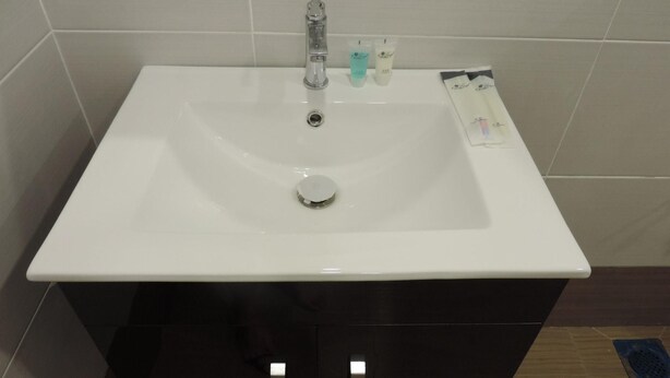 A white bathroom sink with a faucet, a soap dispenser, and a toothbrush holder. - Golden Leaf Boutique Hotel (Johor Bahru)